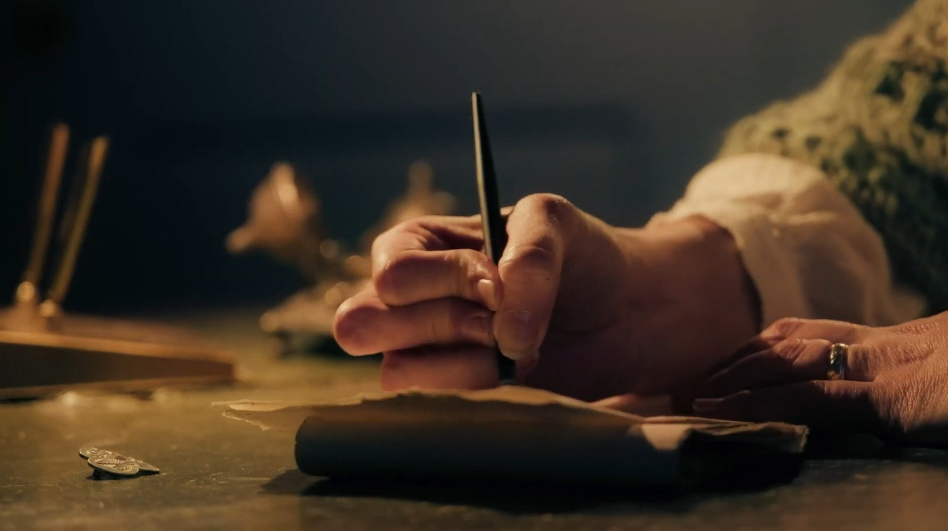 A warmly lit hand writing with a quill